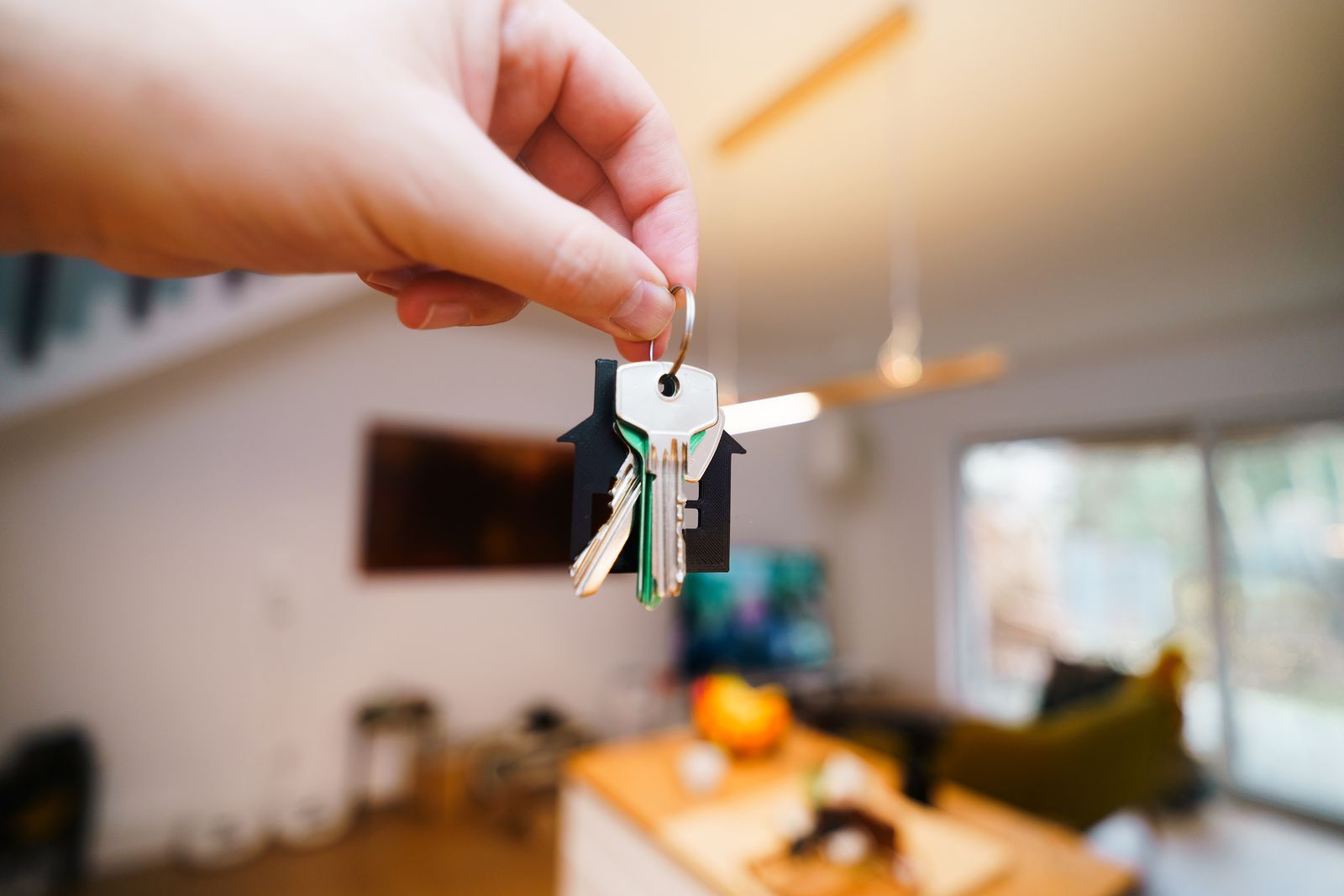 Hand holding house keys inside a modern living space