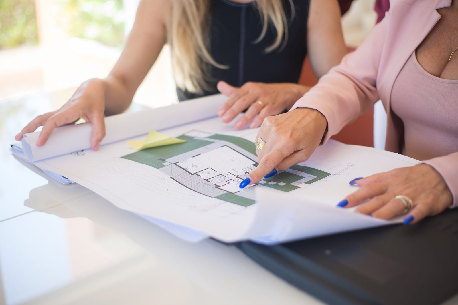 Two people reviewing detailed architectural blueprints